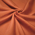 A swirled piece of shiny nylon spandex in the color copper.