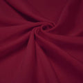 A swirled piece of shiny nylon spandex in the color ebi burgundy.