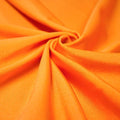 A swirled piece of shiny nylon spandex in the color juicy tangerine.