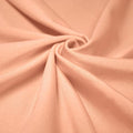 A swirled piece of shiny nylon spandex in the color salmon.