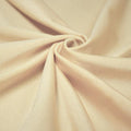 A swirled piece of shiny nylon spandex in the color wheat.