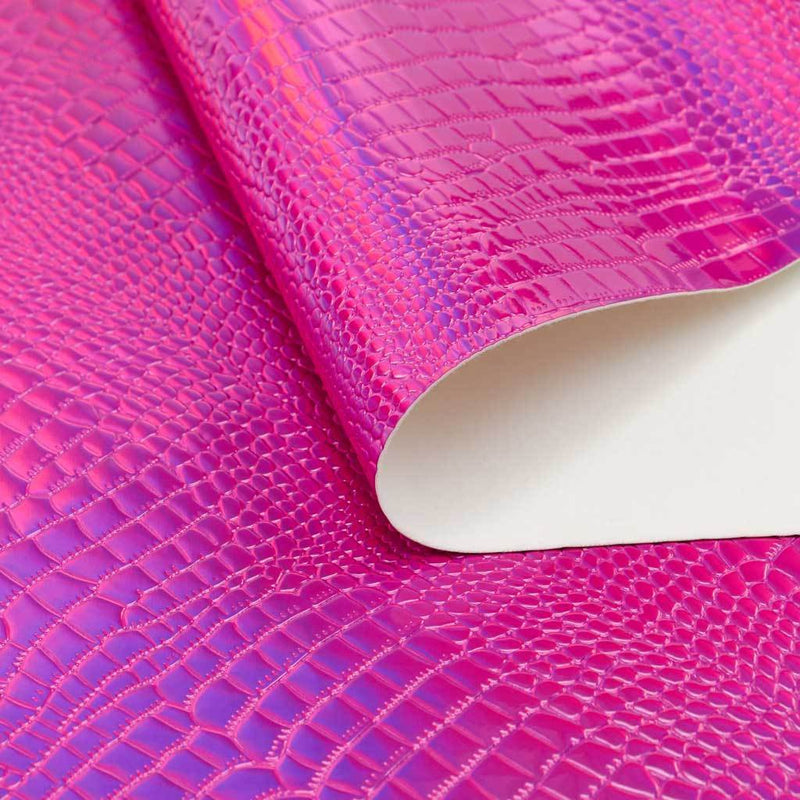 A folded sample of slyther embossed holographic vinyl in the color fuchsia pink.