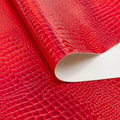 A folded sample of slyther embossed holographic vinyl in the color red.