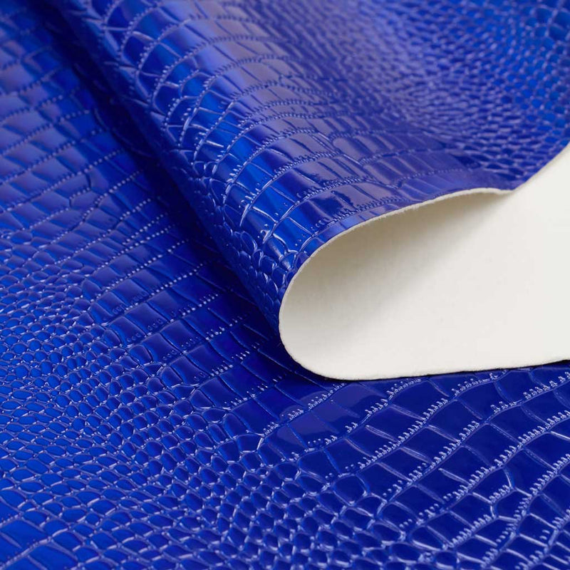 A folded sample of slyther embossed holographic vinyl in the color royal blue.