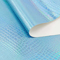 A folded sample of slyther embossed holographic vinyl in the color turquoise blue.