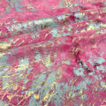 A folded sample of squall foiled tie-dye spandex in the color Bright Pink Gold