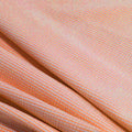 A rippled piece of stretch seersucker material in the color coral.