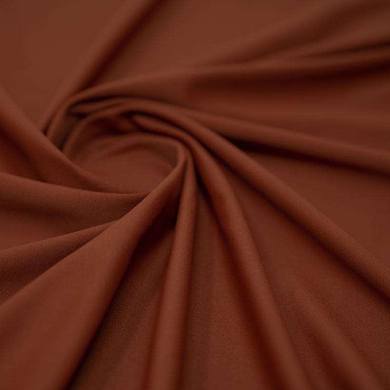 A swirled piece of Synergy Polyester Lycra in the color Clay