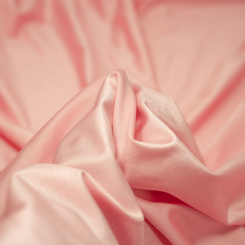 A swirled piece of nylon spandex fabric with an all over shiny look in the color Pinky-Swear