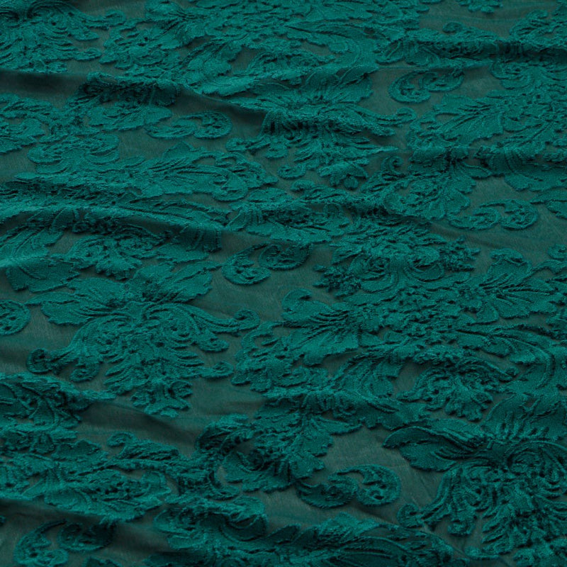 A flat sample of versailles burn out stretch velvet in the color emerald.