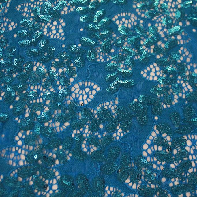 A flat sample of wisteria stretch lace sequin in the color aquamarine.